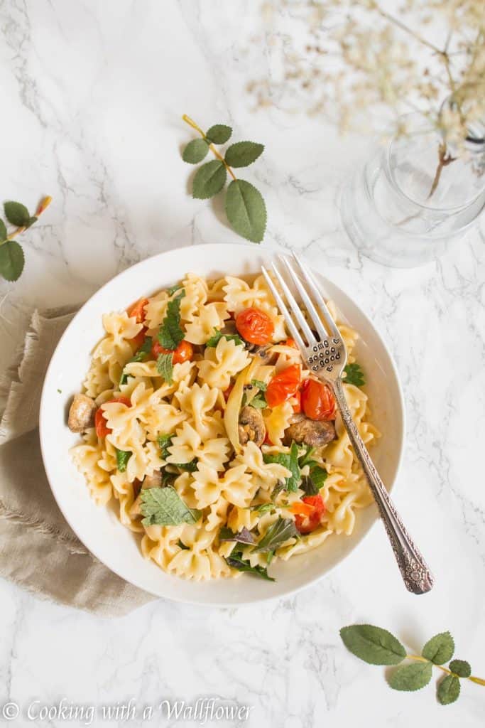 Bow tie pasta tossed with roasted mushrooms, tomatoes, onions, fresh herbs, and a drizzle of olive oil. This roasted mushroom tomato pasta is delicious, and a great choice for a quick and easy weeknight dinner | Cooking with a Wallflower