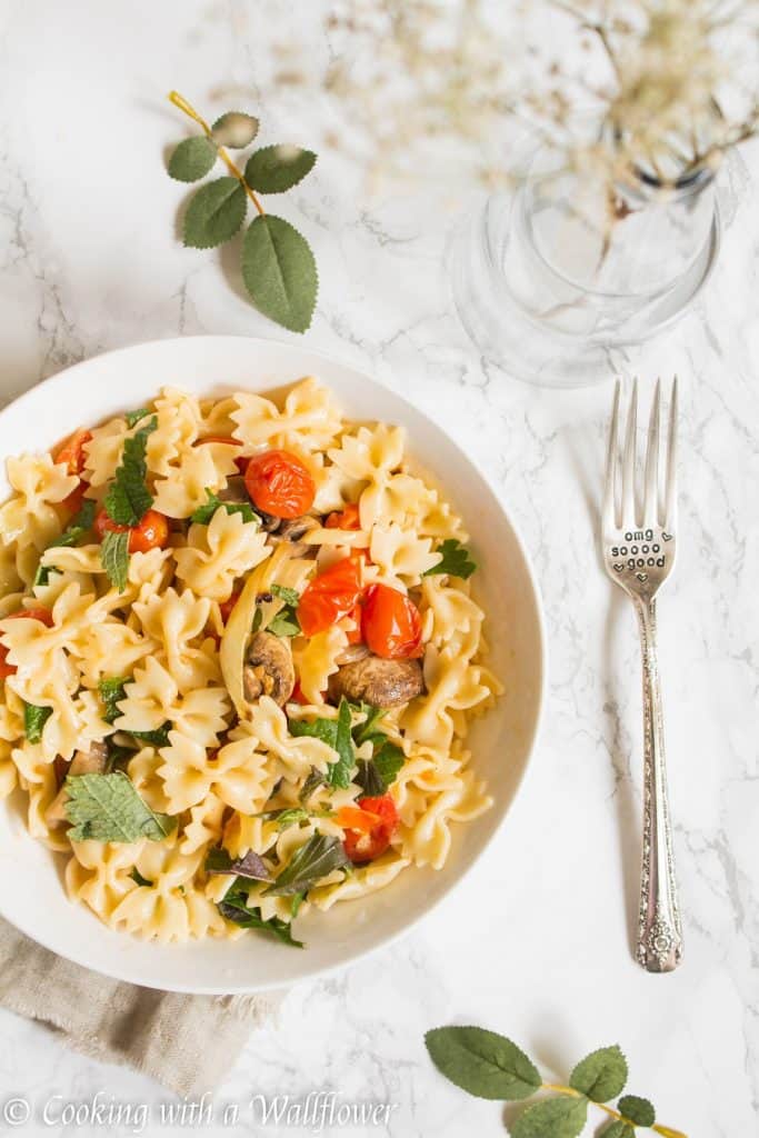 Bow tie pasta tossed with roasted mushrooms, tomatoes, onions, fresh herbs, and a drizzle of olive oil. This roasted mushroom tomato pasta is delicious, and a great choice for a quick and easy weeknight dinner | Cooking with a Wallflower