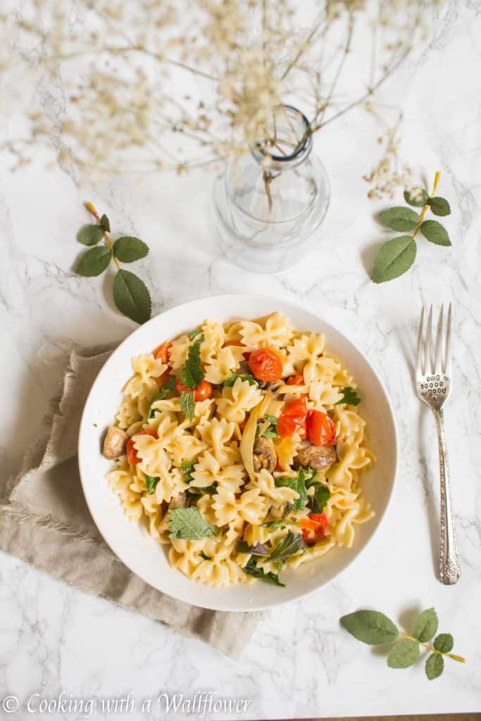 Bow tie pasta tossed with roasted mushrooms, tomatoes, onions, fresh herbs, and a drizzle of olive oil. This roasted mushroom tomato pasta is delicious, and a great choice for a quick and easy weeknight dinner | Cooking with a Wallflower