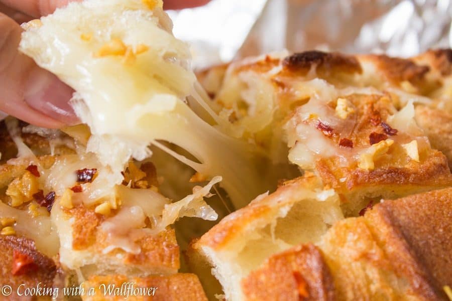 Crusty bread stuffed with shredded mozzarella cheese then brushed with a garlicky butter. This spicy cheesy garlic pull apart bread is simple to make and SO delicious | Cooking with a Wallflower