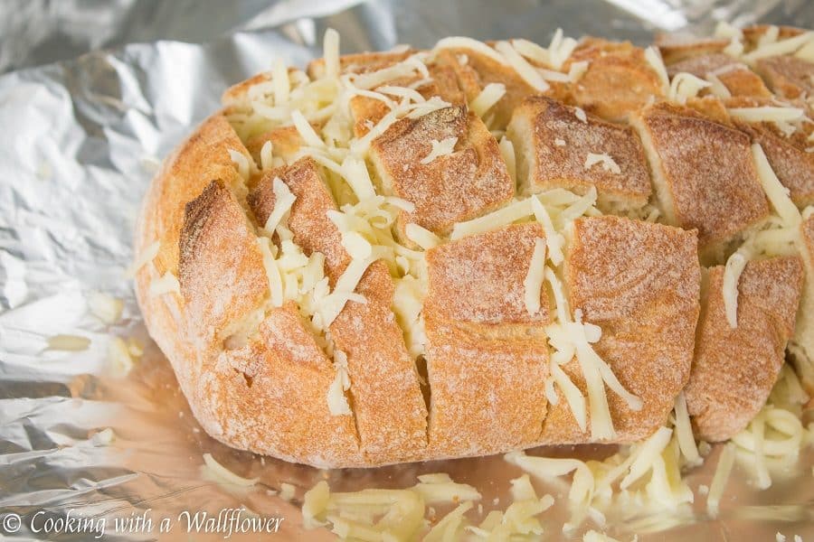 Crusty bread stuffed with shredded mozzarella cheese then brushed with a garlicky butter. This spicy cheesy garlic pull apart bread is simple to make and SO delicious | Cooking with a Wallflower