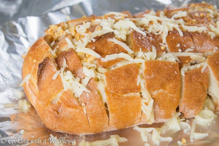 Crusty bread stuffed with shredded mozzarella cheese then brushed with a garlicky butter. This spicy cheesy garlic pull apart bread is simple to make and SO delicious | Cooking with a Wallflower