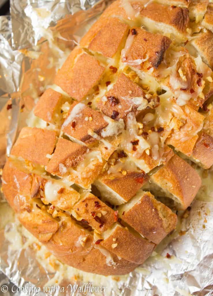 Crusty bread stuffed with shredded mozzarella cheese then brushed with a garlicky butter. This spicy cheesy garlic pull apart bread is simple to make and SO delicious | Cooking with a Wallflower