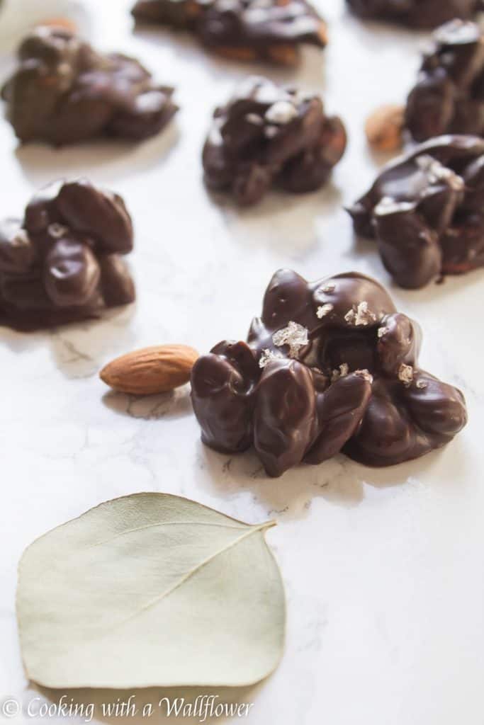 Roasted almonds coated with semi sweet chocolate then topped with a pinch of vanilla salt. These chocolate covered almond clusters are so simple to make and perfect for gifting. | Cooking With a Wallflower