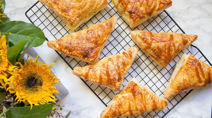 Puff pastries filled with cinnamon apples and drizzled with salted caramel, these salted caramel apple turnovers are simple to make and delicious. | Cooking with a Wallflower