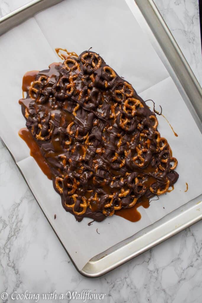 Semi sweet chocolate bark piled with mini pretzels and drizzled with salted caramel. This salted caramel pretzel bark is simple to make and the perfect sweet and savory snack. | Cooking with a Wallflower