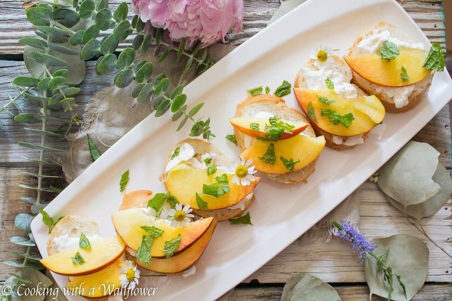 Crispy bread topped with fresh peaches, creamy burrata, mint and a sweet, tangy, honey, lemon dressing. Super fresh, easy to make, and pleasantly delicious, this peach burrata toast is the perfect appetizer for guests. | Cooking with a Wallflower